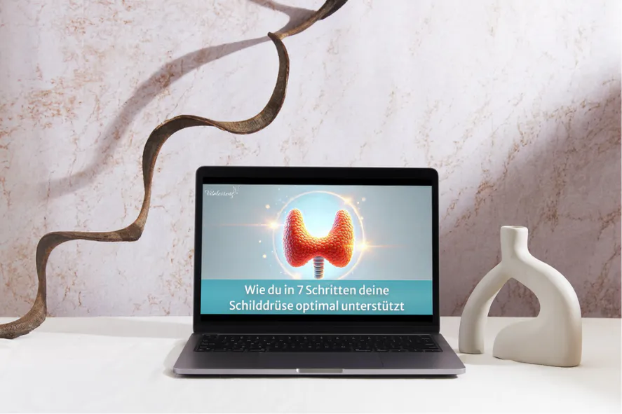 Laptop mit Schilddrüsentraining auf Tisch mit Vase